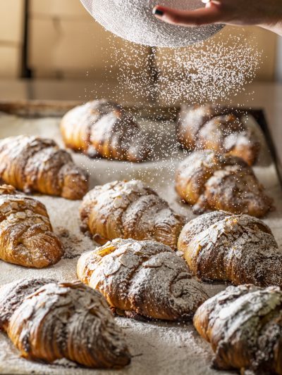 Scrumptious almond croissant on a wooden board, showcasing its flaky layers and almond filling